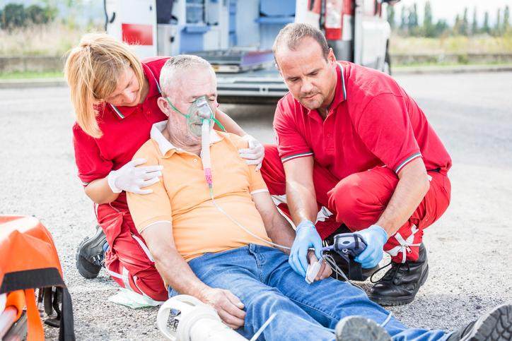 Ambulansepersonell ved siden av en kollapset pasient