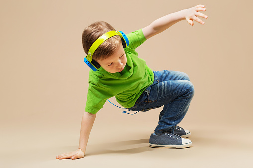 En gutt i grønn skjorte med hodetelefoner på danser breakdance