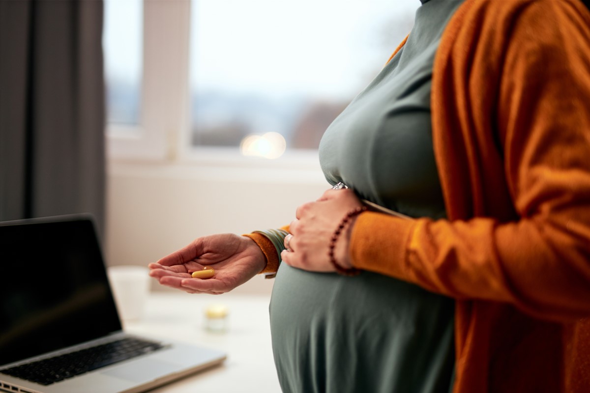 En gravid kvinne holder medisiner i hånden og vet ikke hvilke som er egnet med tanke på sikkerhet.