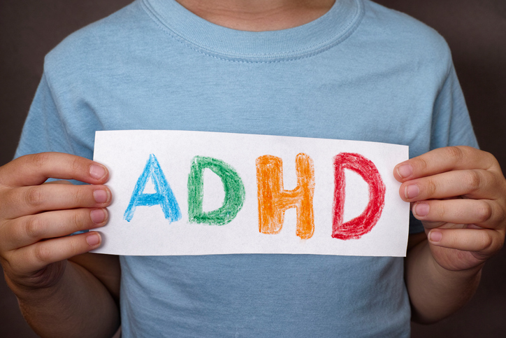 En gutt holder et skilt med et fargerikt ADHD-tegn på