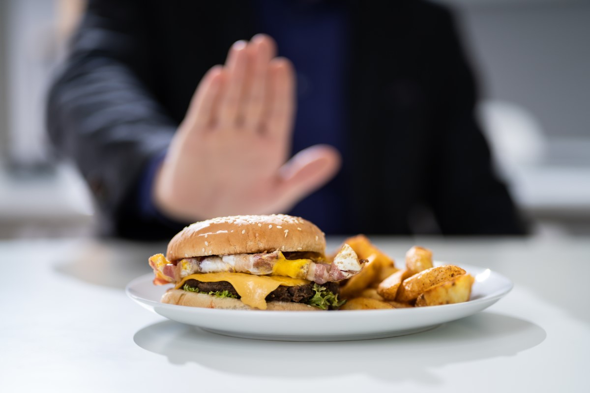 Upassende mat som årsak til halsbrann - en hamburger på en tallerken som en mann nekter å spise